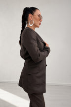 Woman wearing a brown coat against a white background