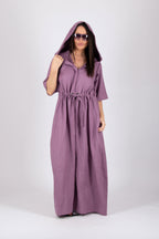 Woman wearing a long purple jumpsuit with a hood on a white background