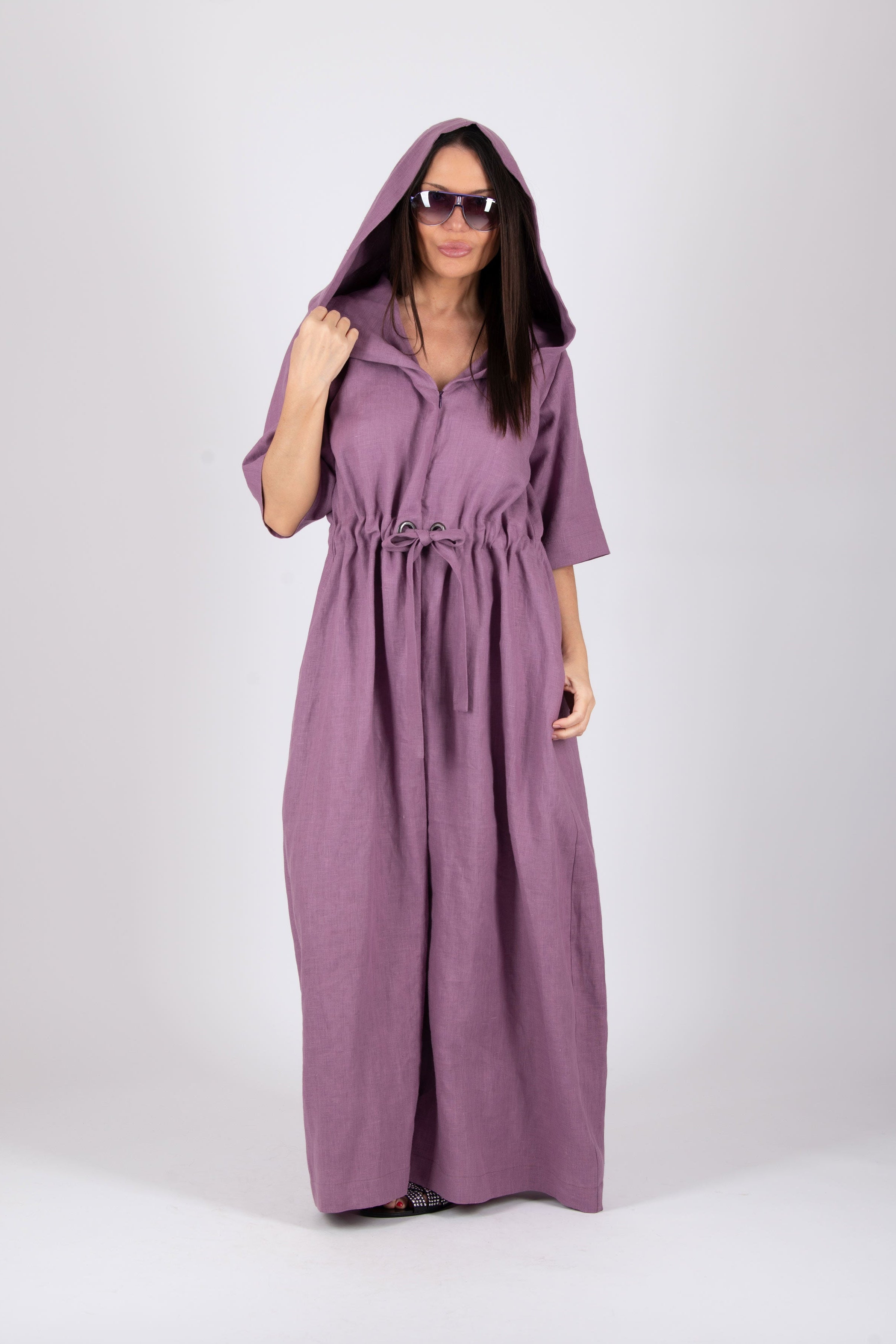 Woman wearing a long purple jumpsuit with a hood on a white background