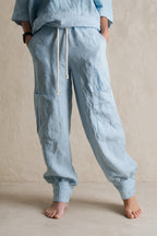 Light blue linen pants worn by a person on a beige background