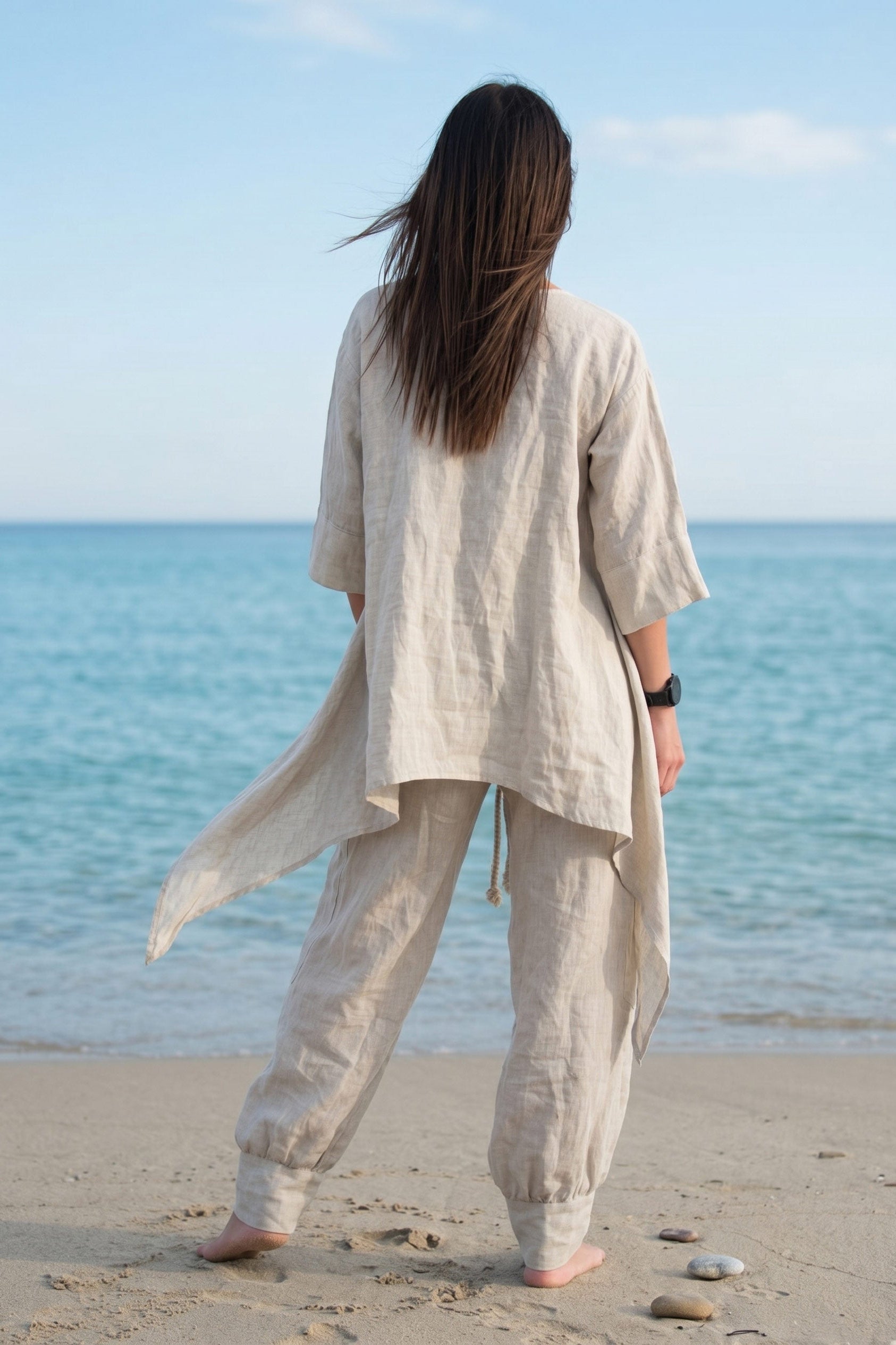 Person wearing a beige linen outfit standing on a beach with ocean view