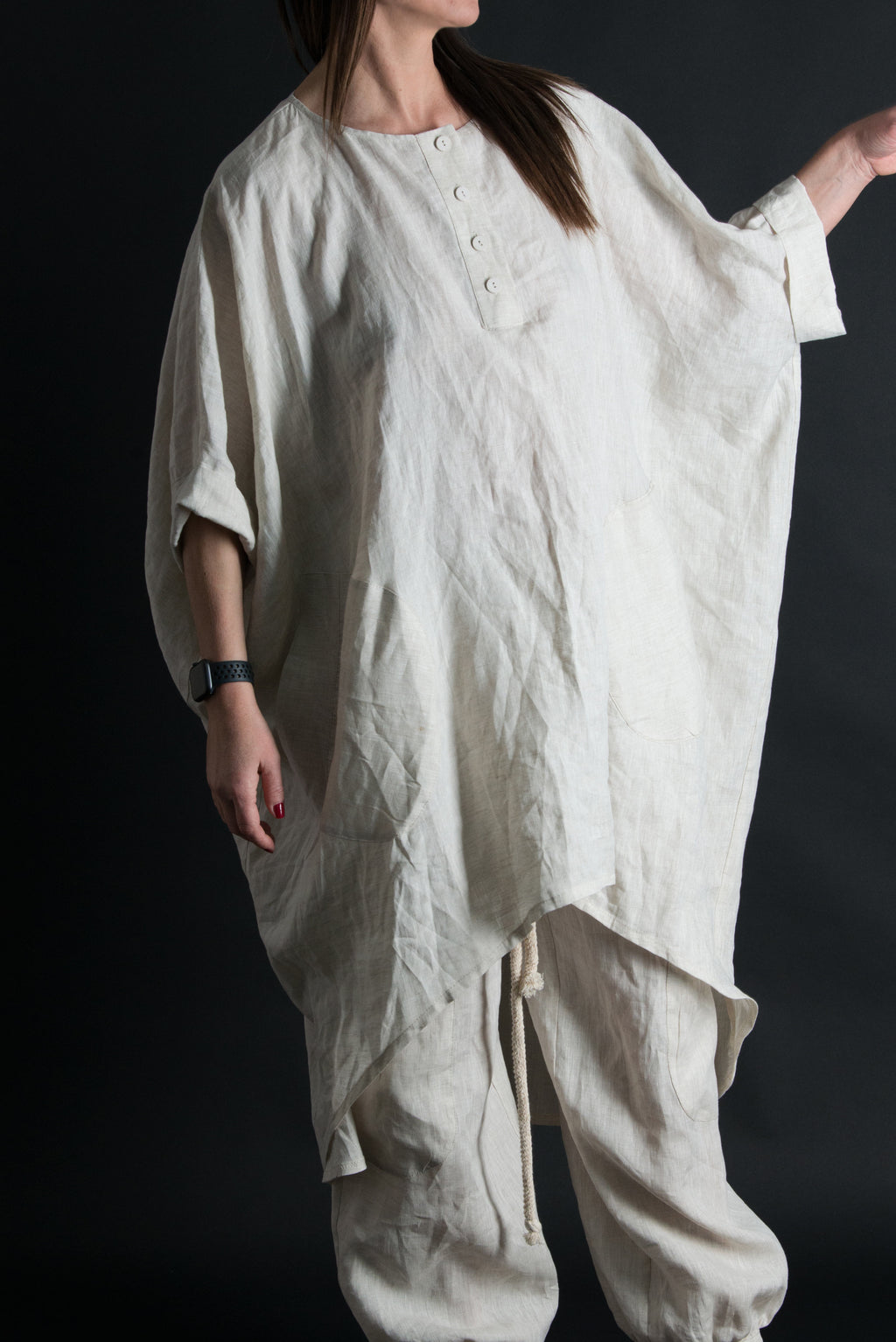 Person wearing a loose-fitting beige outfit against a black background