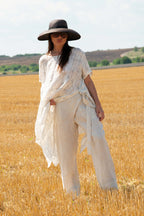 Woman in a white outfit and black hat standing in a golden field