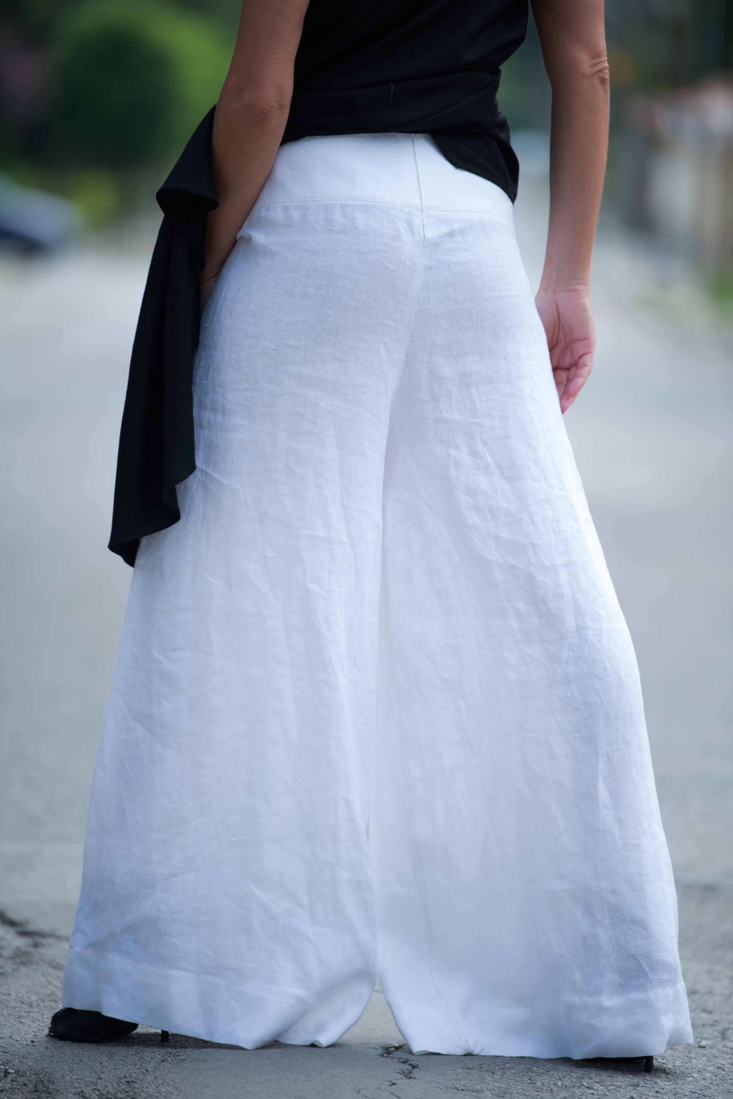 Person wearing a black top and white wide-leg pants on a blurred street background