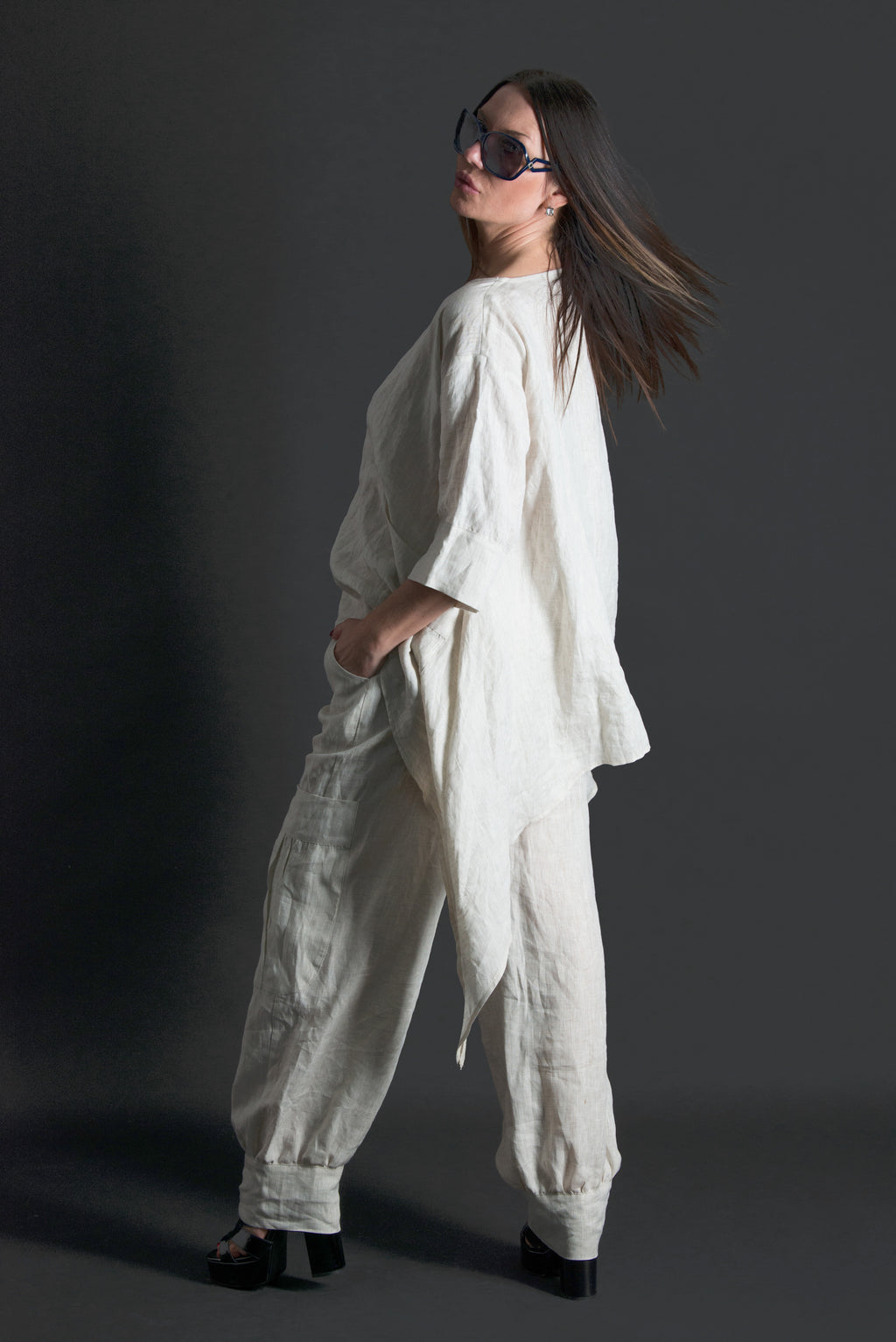 Woman wearing a natural linen outfit against a dark background