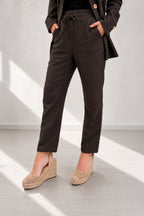 Person wearing dark brown pants and a matching coat on a light gray background