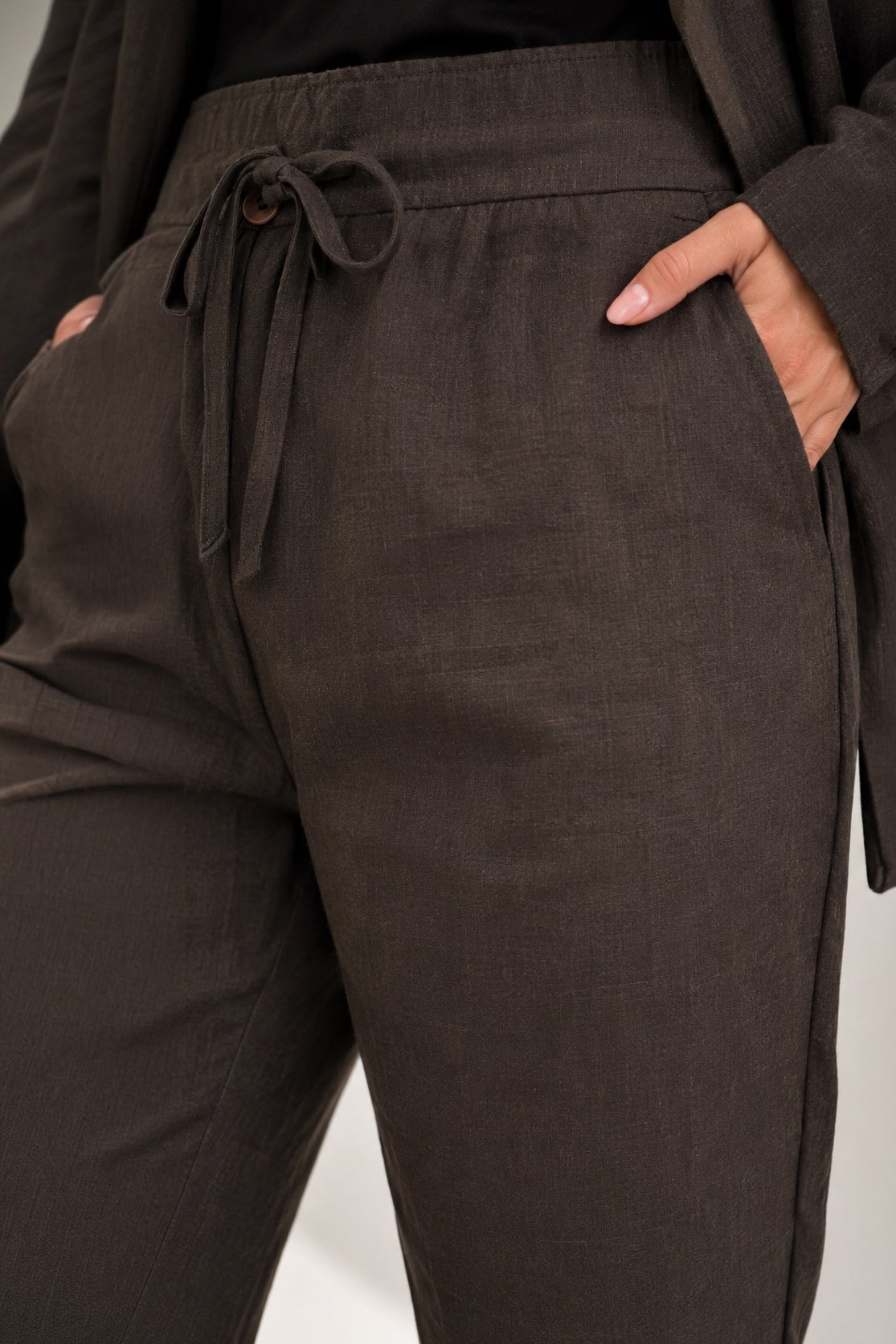 Dark brown pants with a drawstring waist on a light gray background
