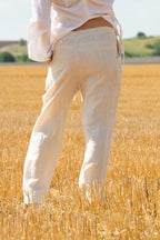 Person wearing white pants standing in a field of golden wheat