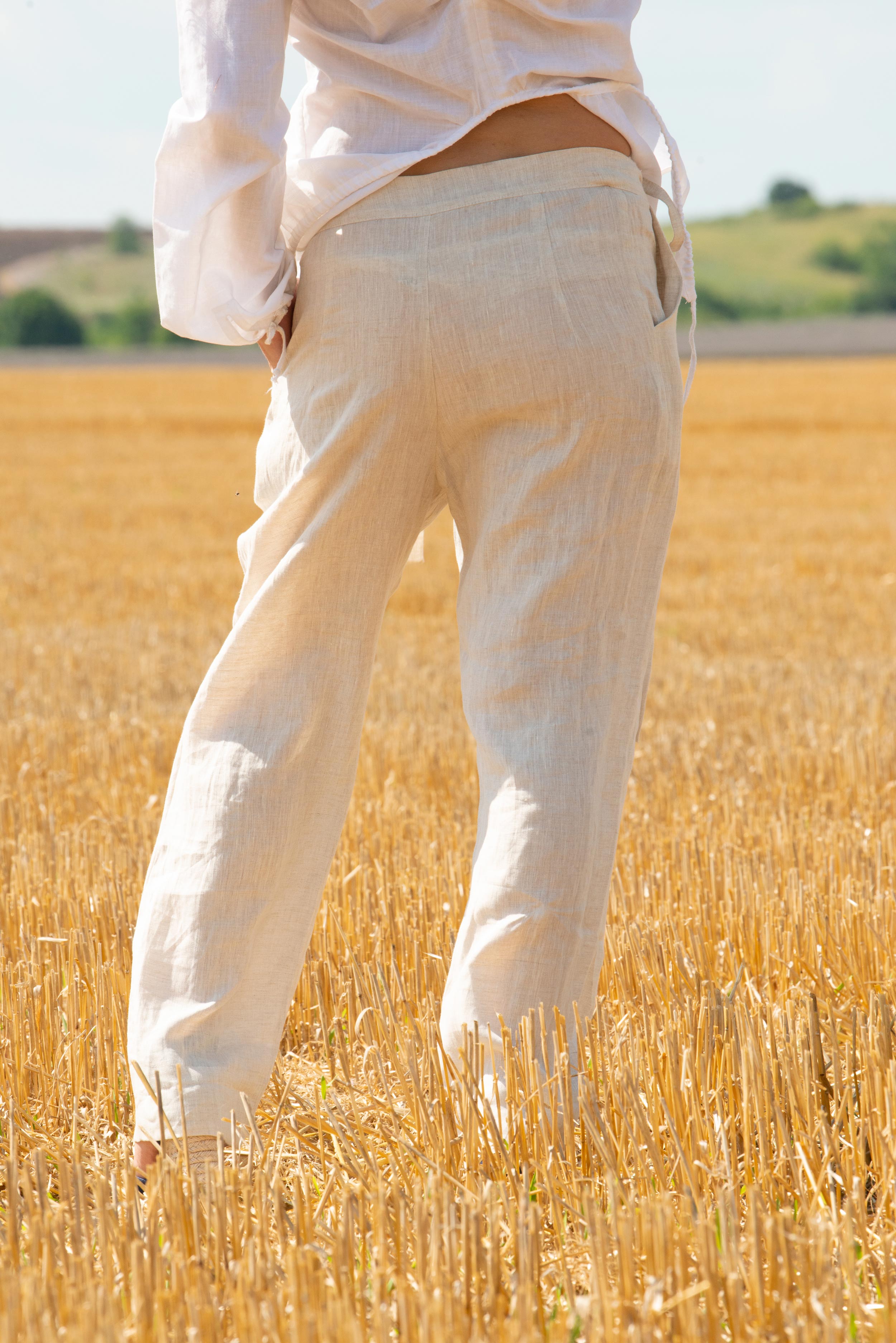 Person wearing white pants standing in a field of golden wheat