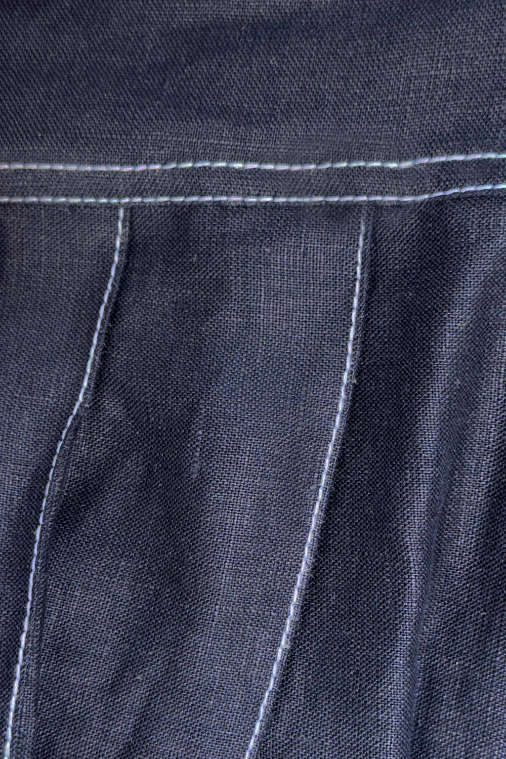 Close-up of dark denim fabric with white stitching
