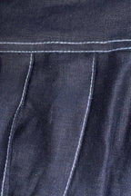 Close-up of dark denim fabric with white stitching