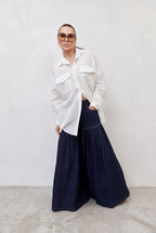 Person wearing a white shirt and dark blue pants against a plain background