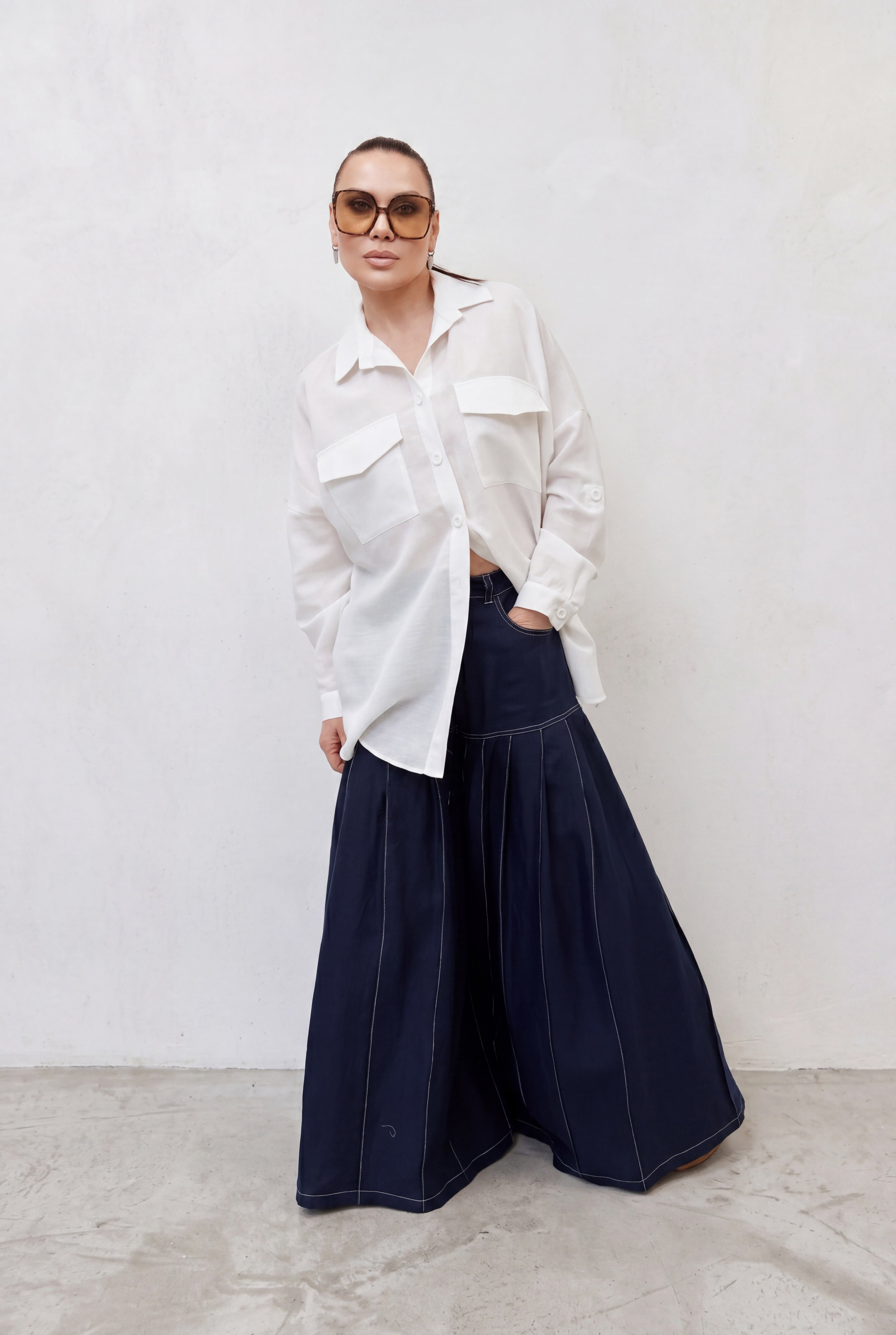 Person wearing a white shirt and dark blue pants against a plain background