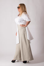 Woman wearing a white blouse and beige wide-leg pants against a white background