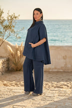 Woman in a navy blue outfit standing on a beach with ocean in the background