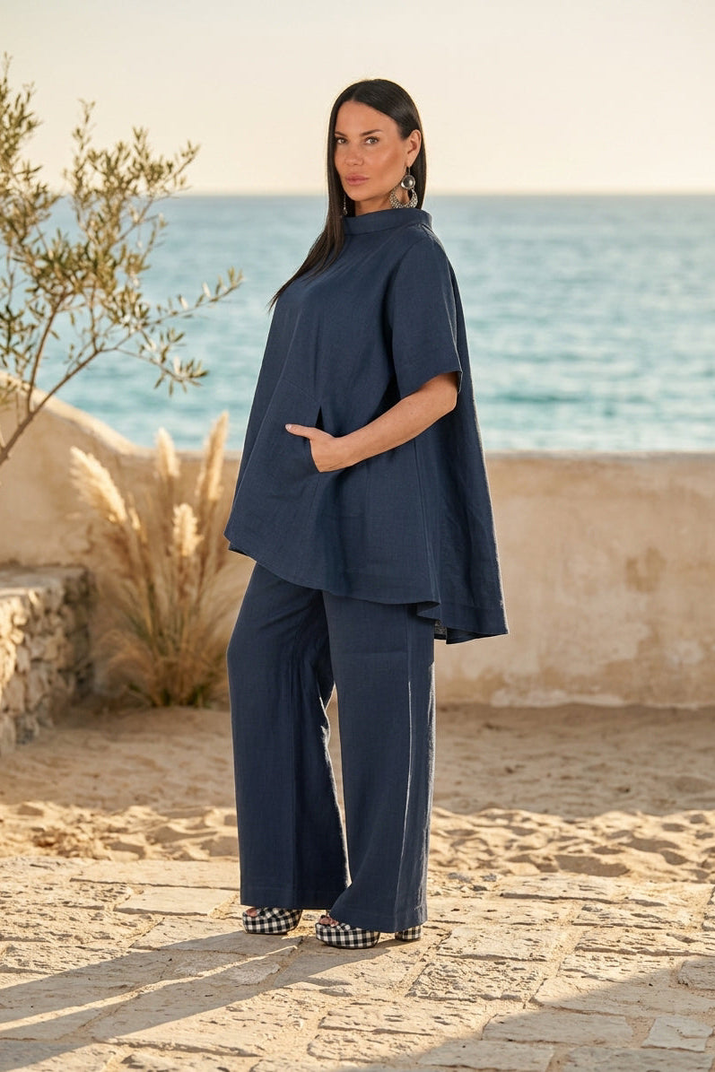 Woman in a navy blue outfit standing on a beach with ocean in the background