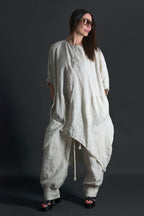 Woman wearing a loose-fitting natural linen outfit against a dark background