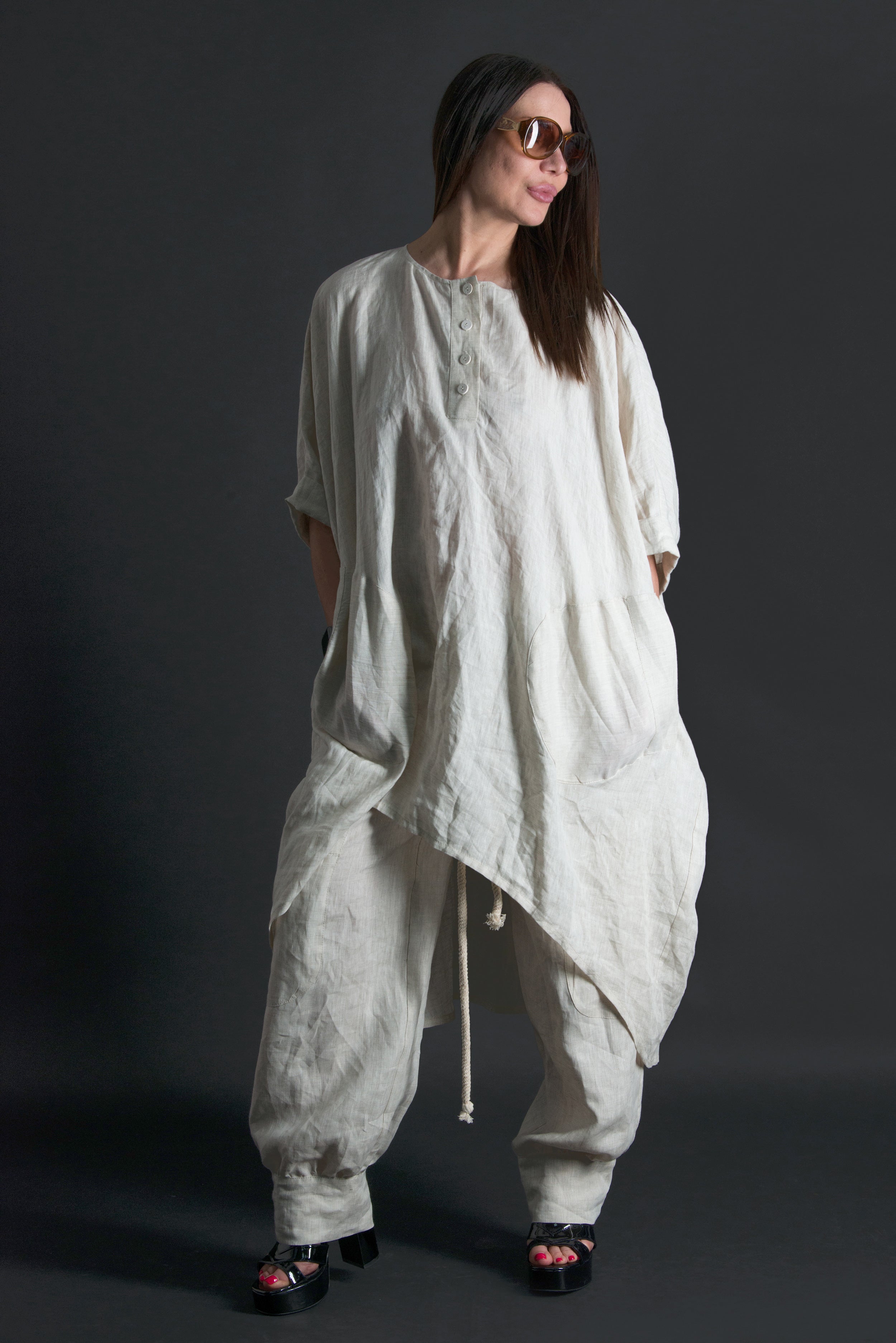 Woman wearing a loose-fitting natural linen outfit against a dark background