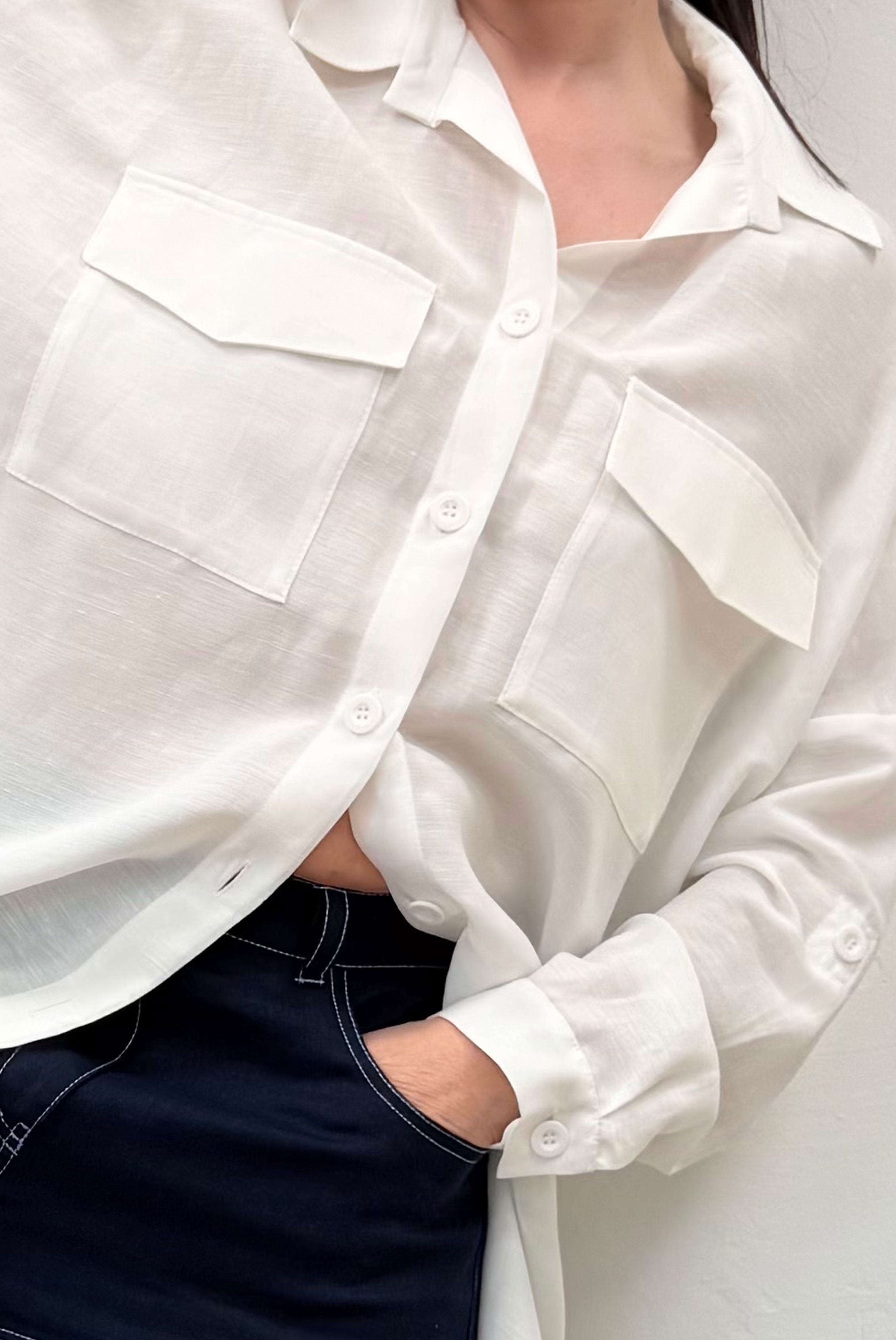 Close-up of a person wearing a white button-up shirt with rolled-up sleeves.