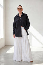 Person wearing a black shirt and white pants in a bright room