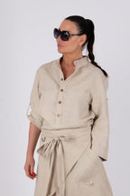 Woman wearing a beige outfit with sunglasses on a white background
