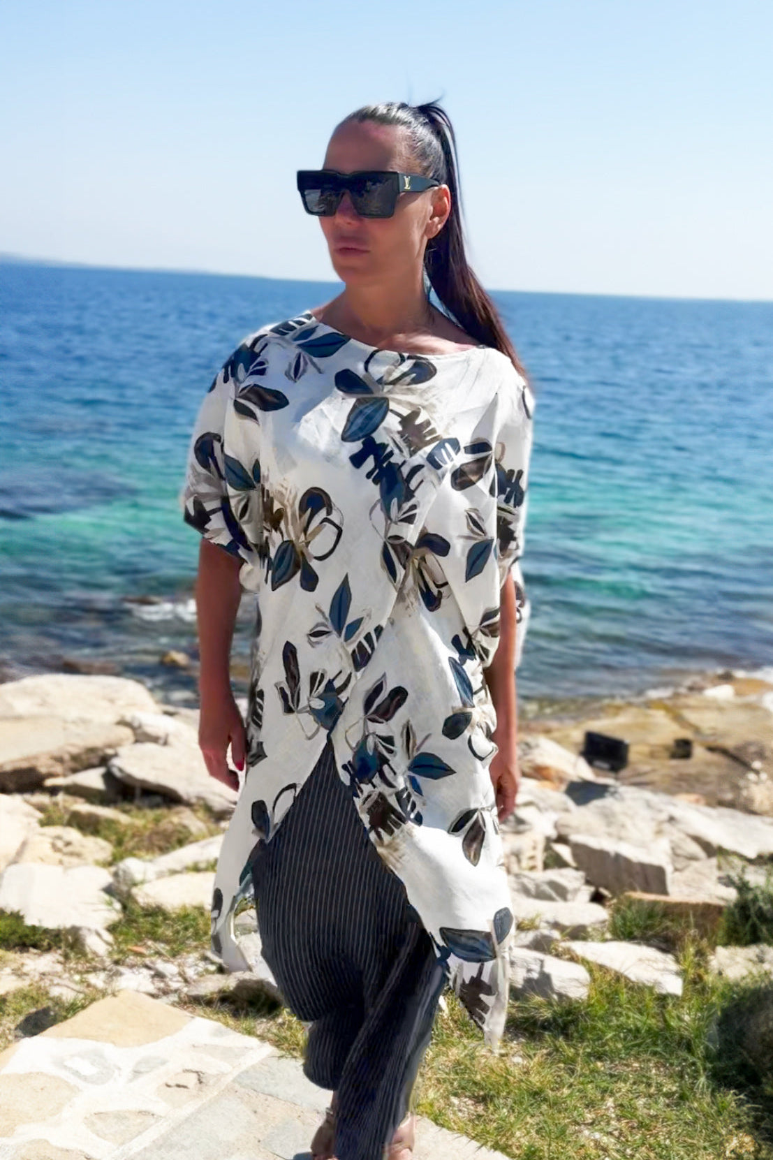 Woman in a floral tunic standing by the ocean