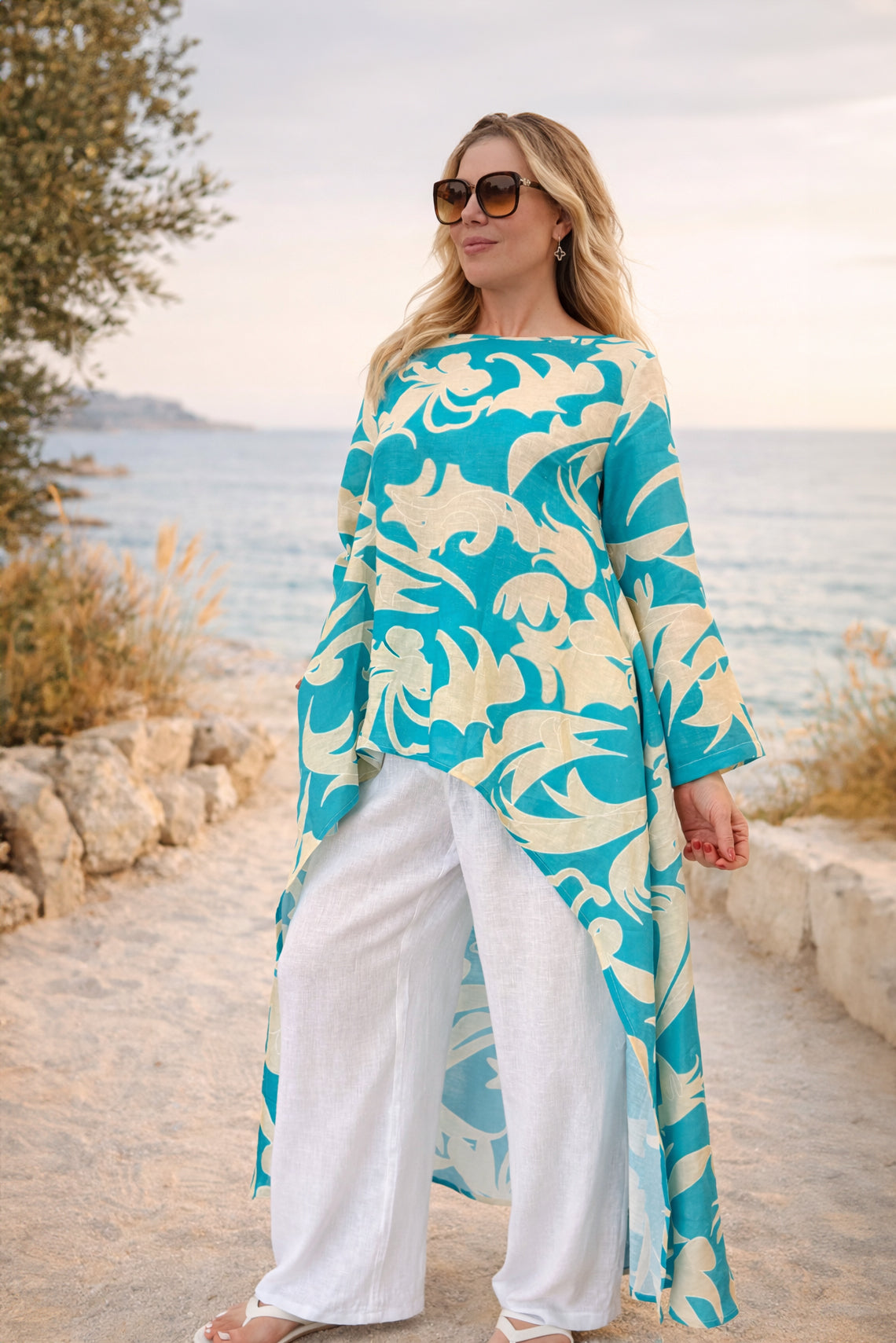 Woman wearing a blue and white floral dress standing on a beach.