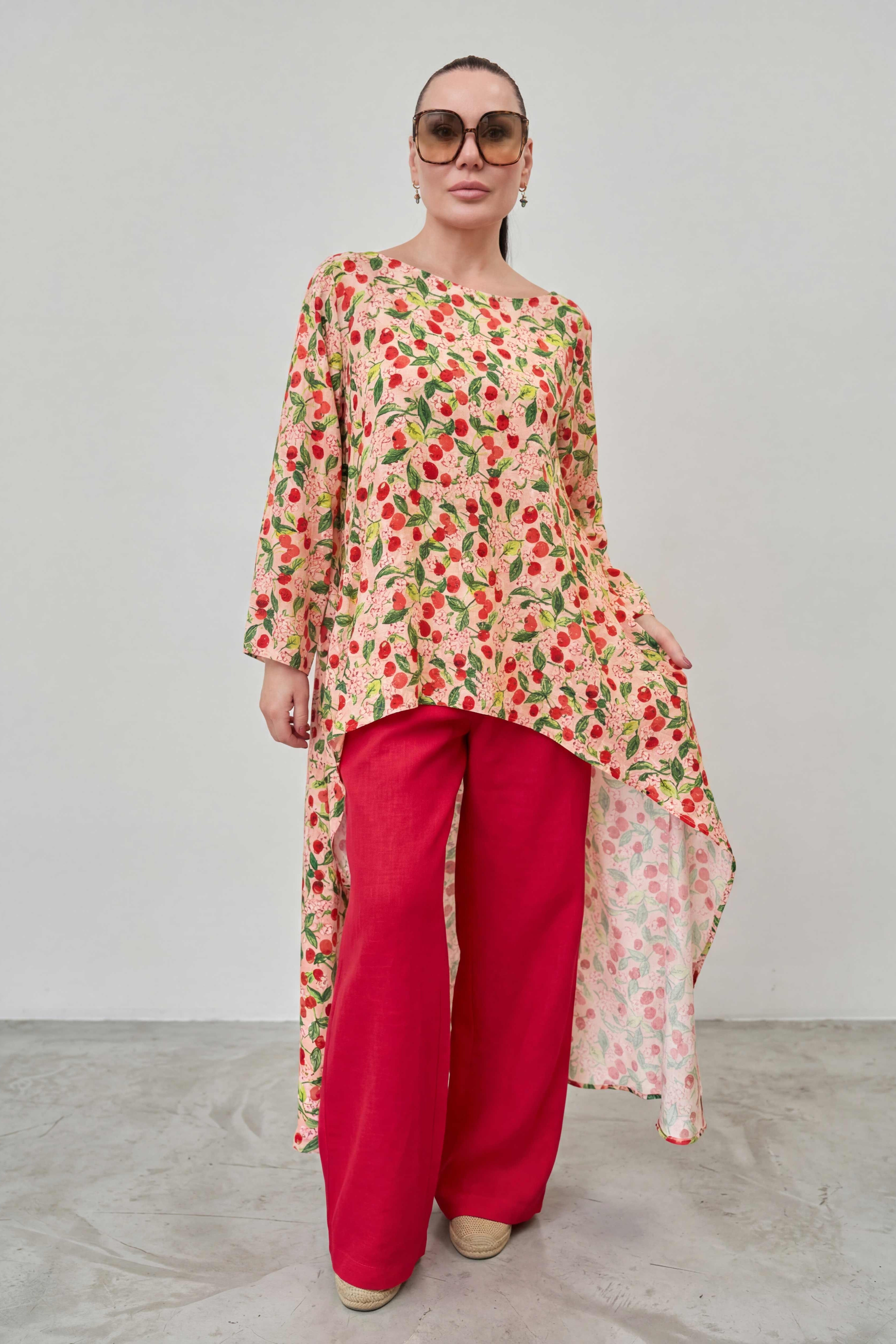 Woman wearing a floral top and red pants against a plain background