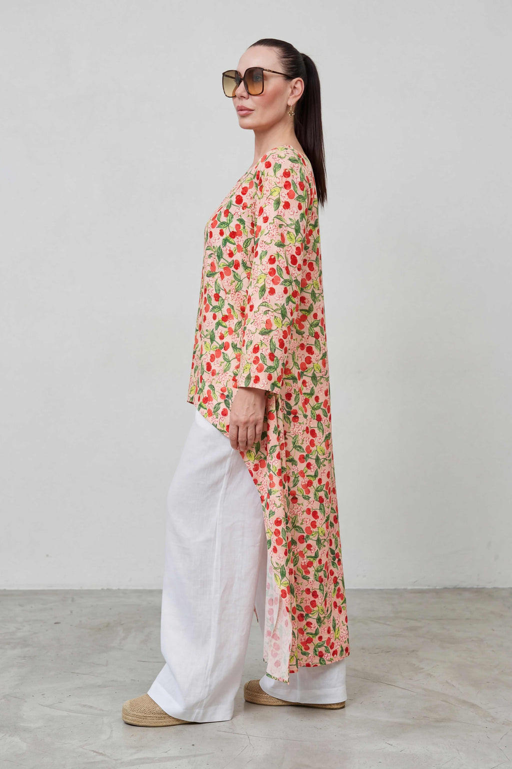 Woman wearing a floral dress and sunglasses against a plain background