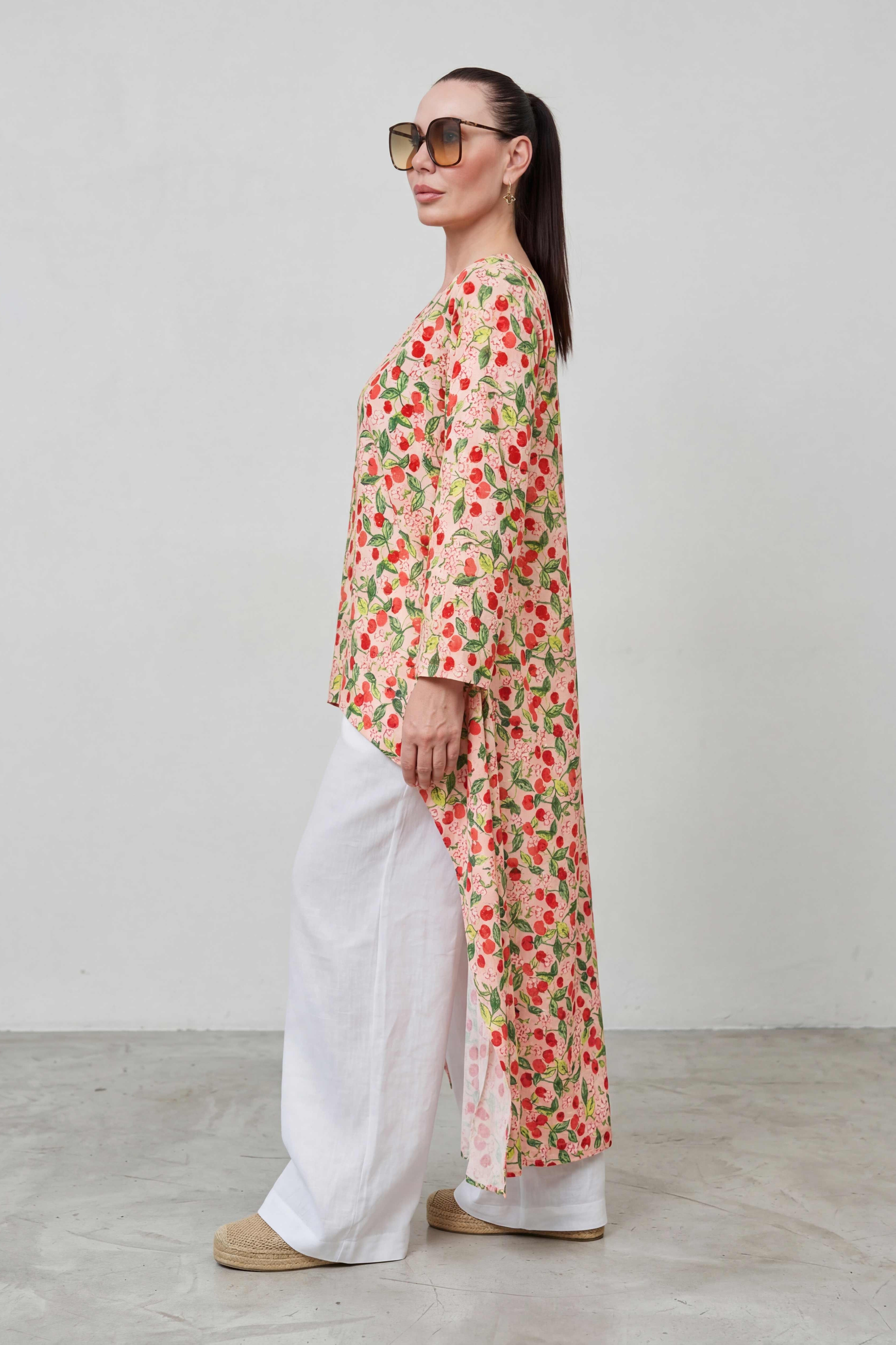 Woman wearing a floral dress and sunglasses against a plain background