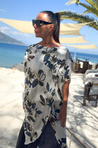 Woman wearing a floral dress by the beach with palm trees and blue sky in the background