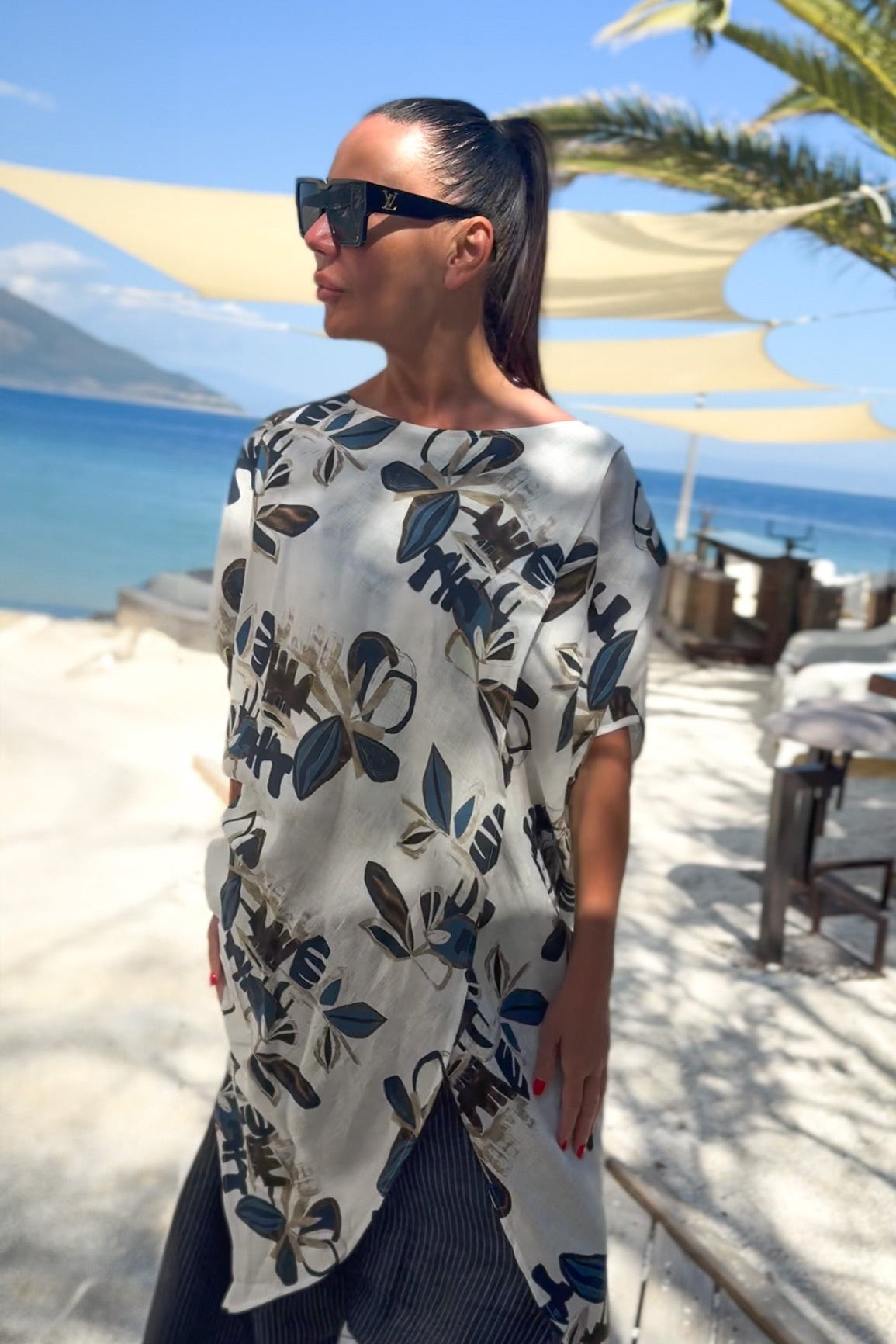 Woman wearing a floral dress by the beach with palm trees and blue sky in the background