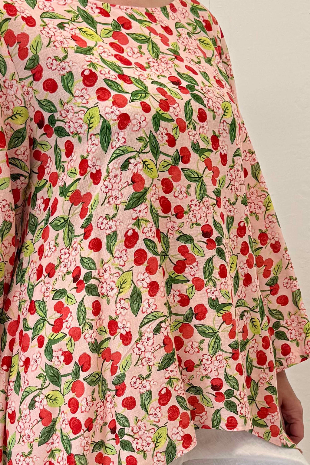 Floral patterned fabric with red cherries on a light background