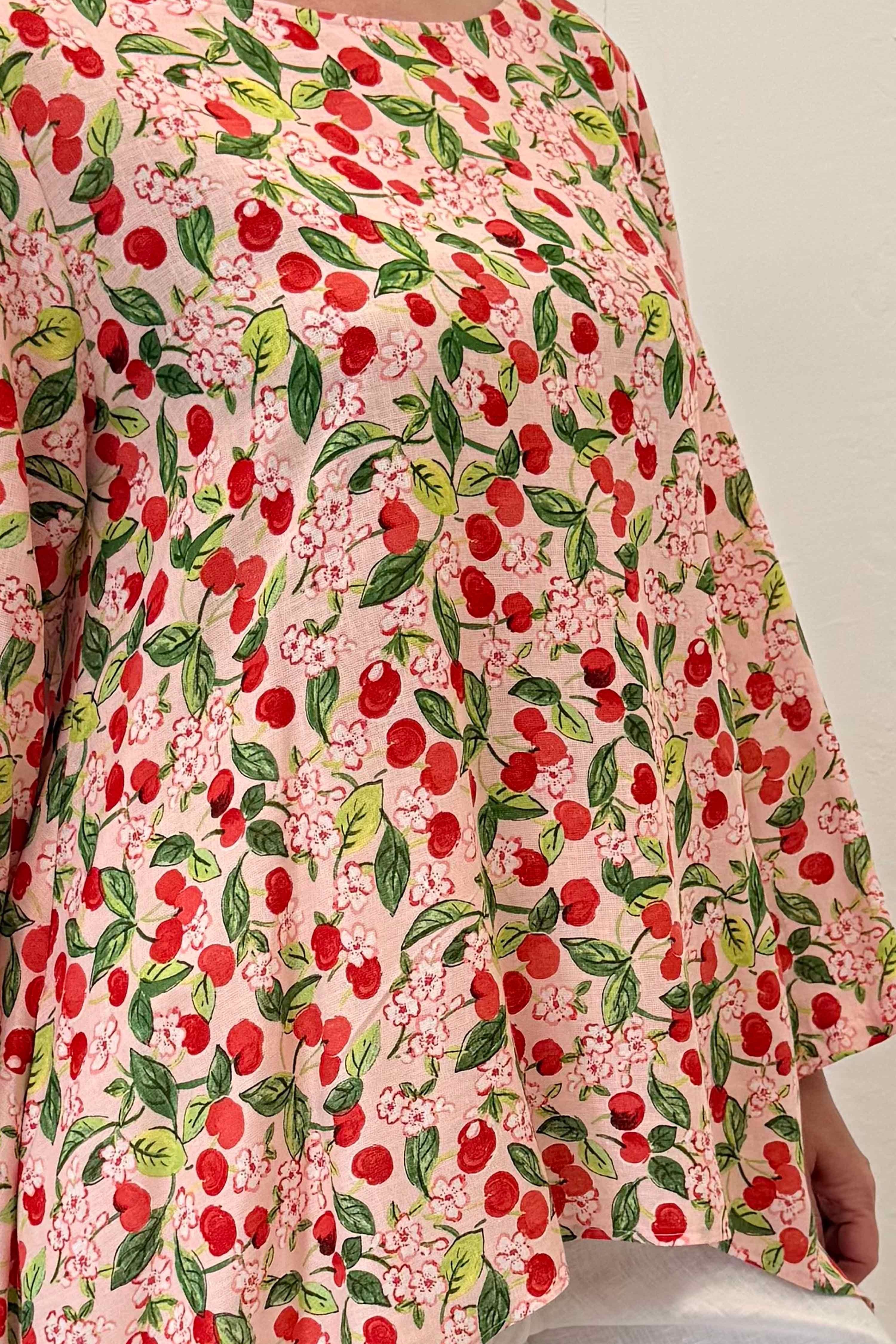 Floral patterned fabric with red cherries on a light background