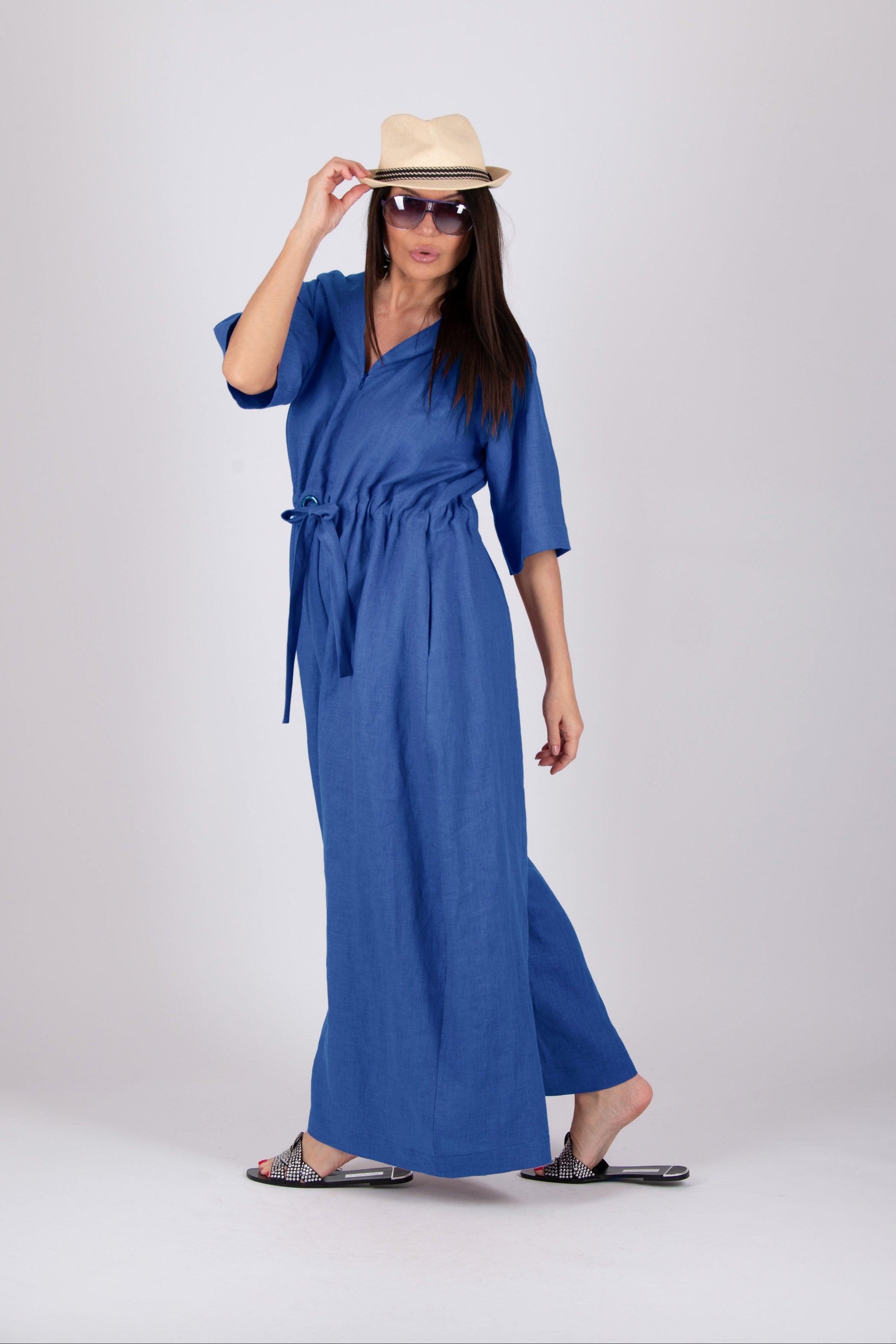 Woman wearing a blue dress and beige hat on a white background