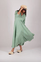 Woman wearing a long green dress and straw hat on a white background