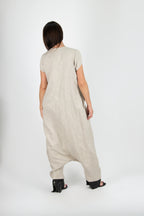 Person wearing a beige jumpsuit with a plain white background