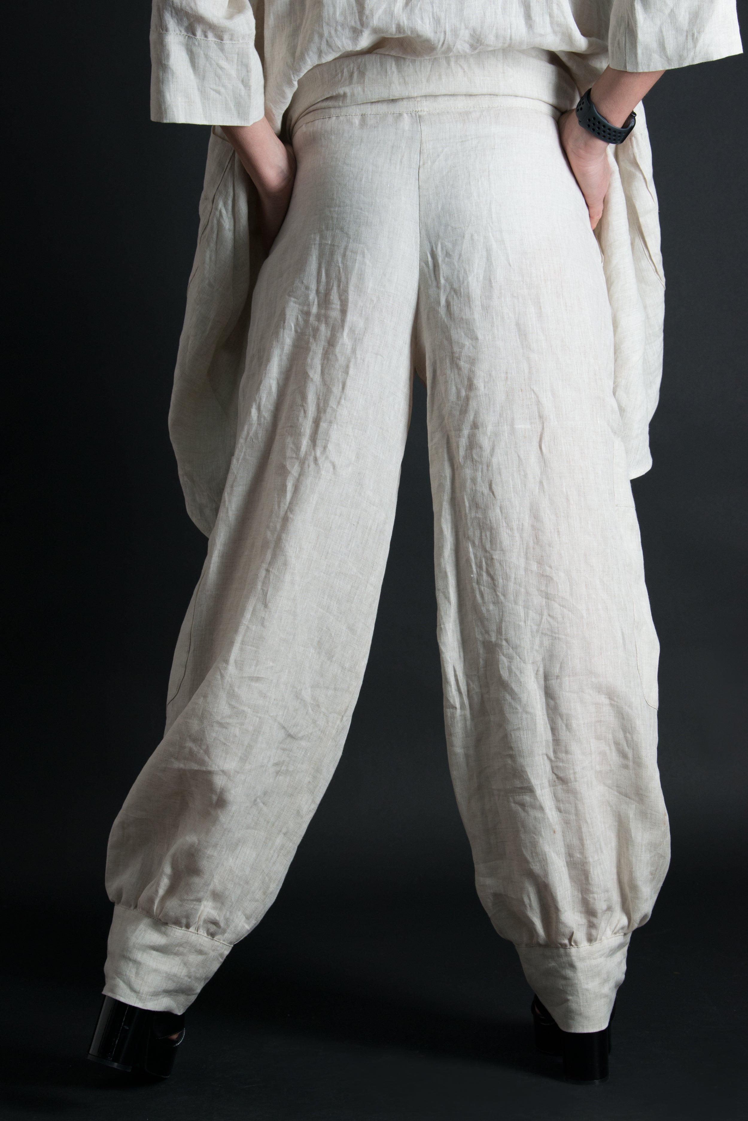 Person wearing beige wide-leg pants against a black background