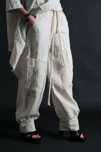 Person wearing white baggy pants with a black background