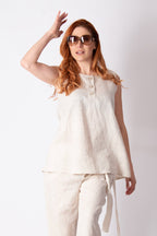 Woman wearing a white sleeveless top and pants on a white background