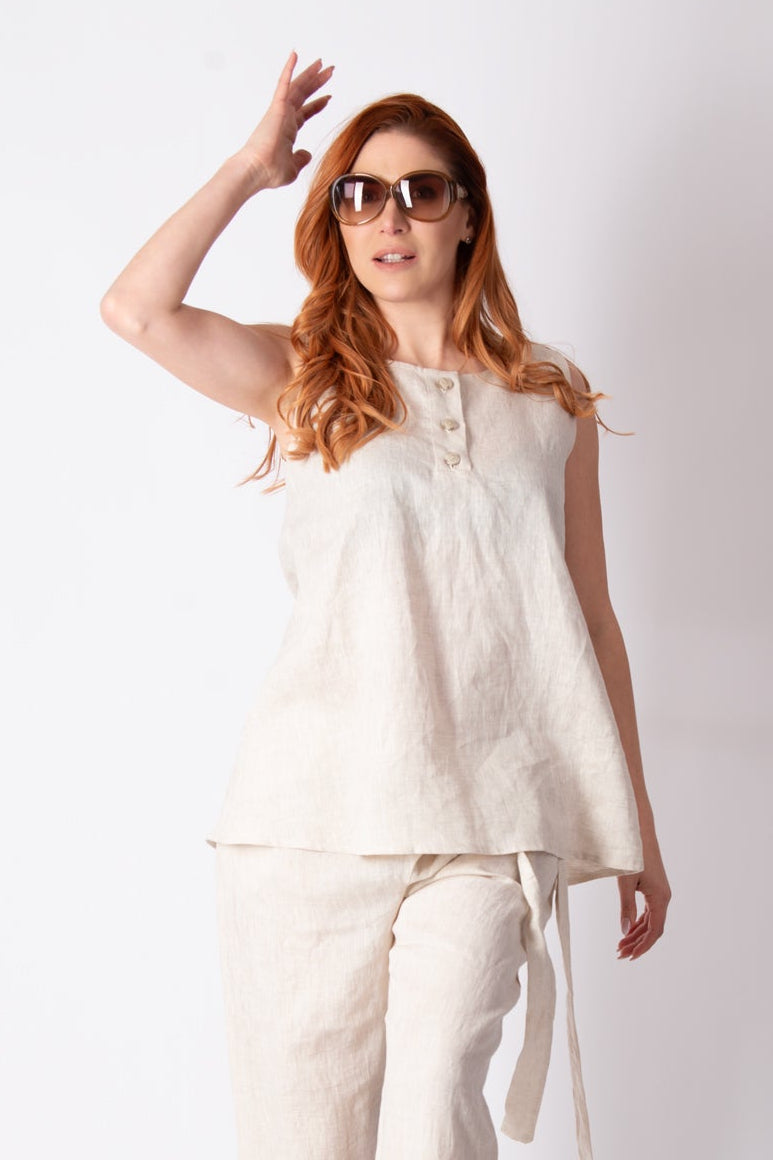 Woman wearing a white sleeveless top and pants on a white background
