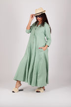 Woman wearing a long green dress and a hat on a white background