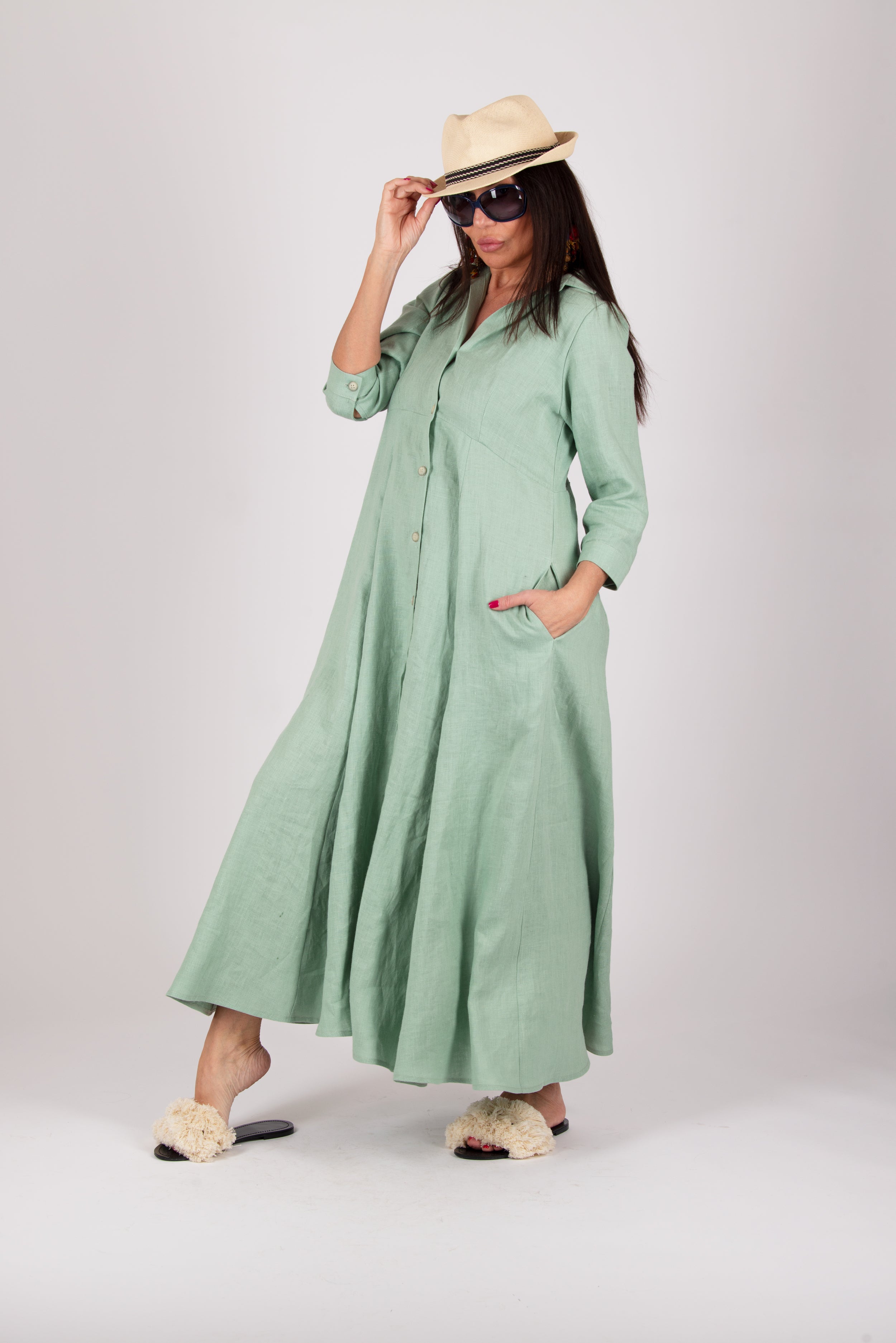 Woman wearing a long green dress and a hat on a white background