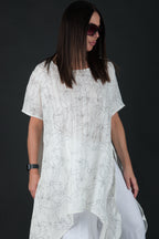 Woman wearing a white patterned dress against a black background