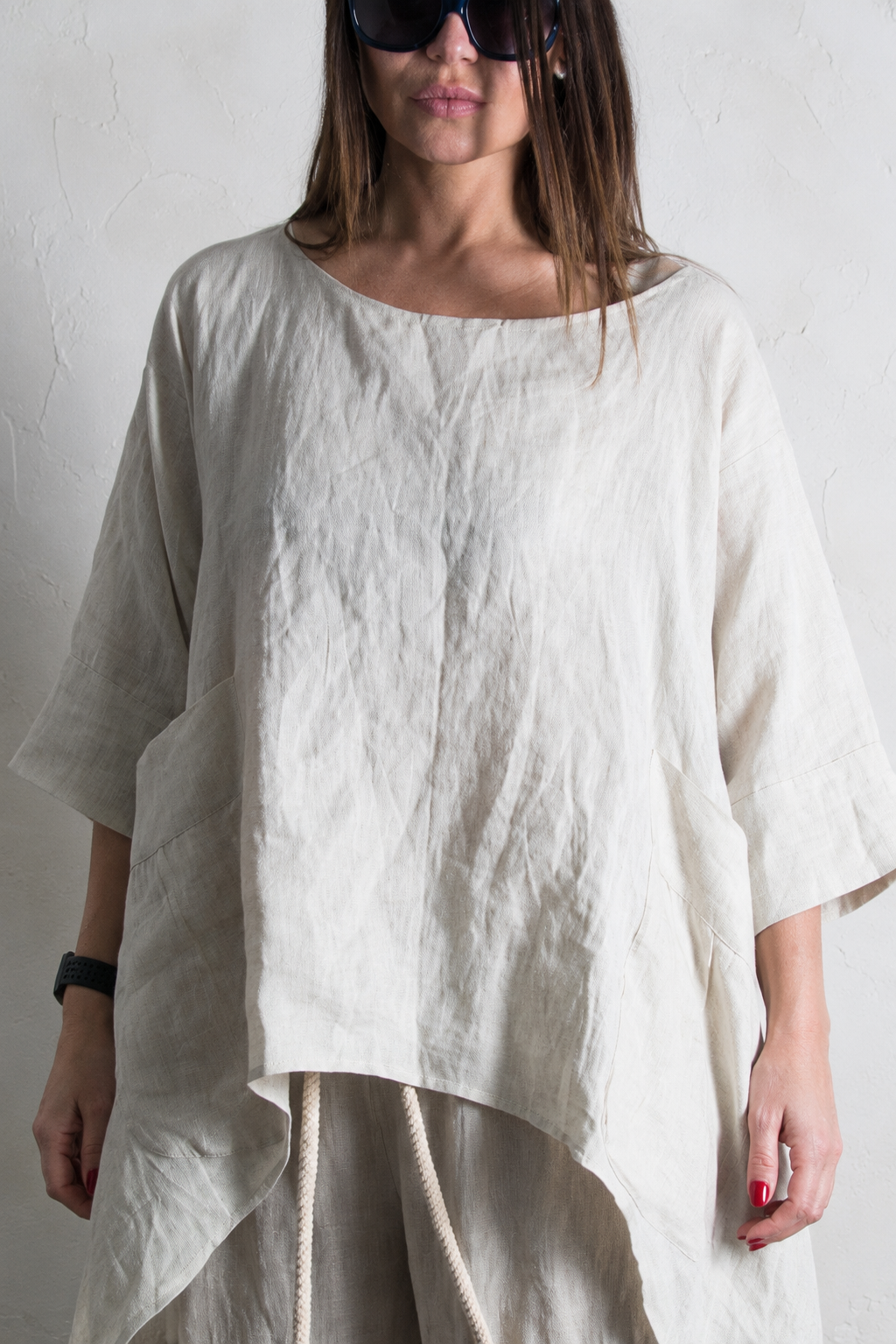Person wearing a loose-fitting beige linen top and pants against a plain background