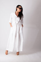 Woman wearing a white jumpsuit against a plain background