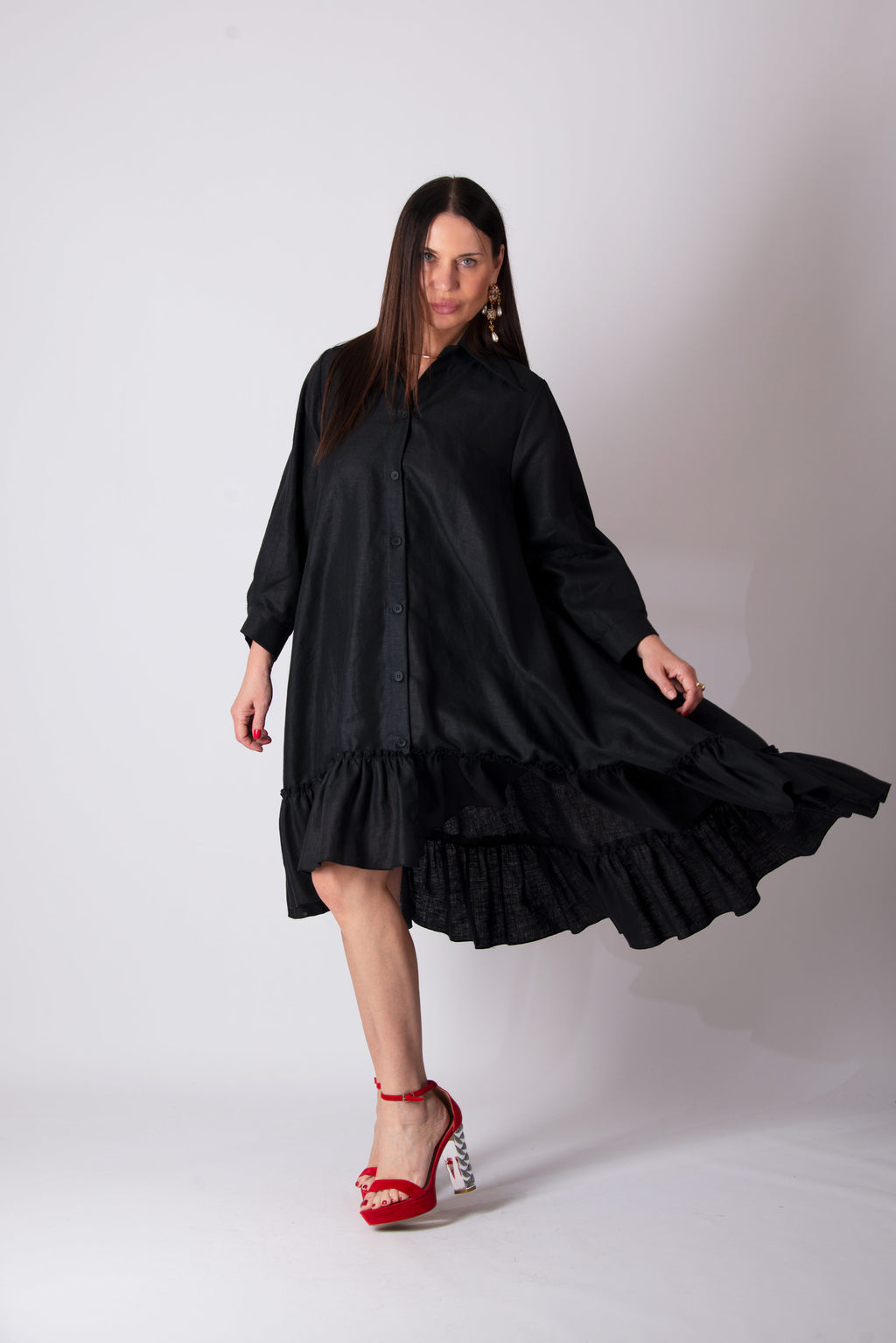 Woman wearing a black dress with ruffled layers on a white background