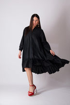 Woman wearing a black dress with ruffled layers on a white background