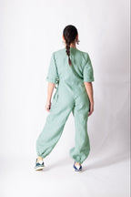 Person wearing a light green jumpsuit on a white background