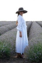 Woman in a white dress and wide-brimmed hat standing in a lavender field.